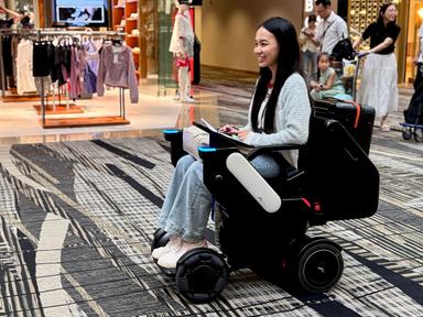 Eine Passagierin nutzt einen autonom fahrenden WHILL-Rollstuhl im Transitbereich des Flughafens Changi.
